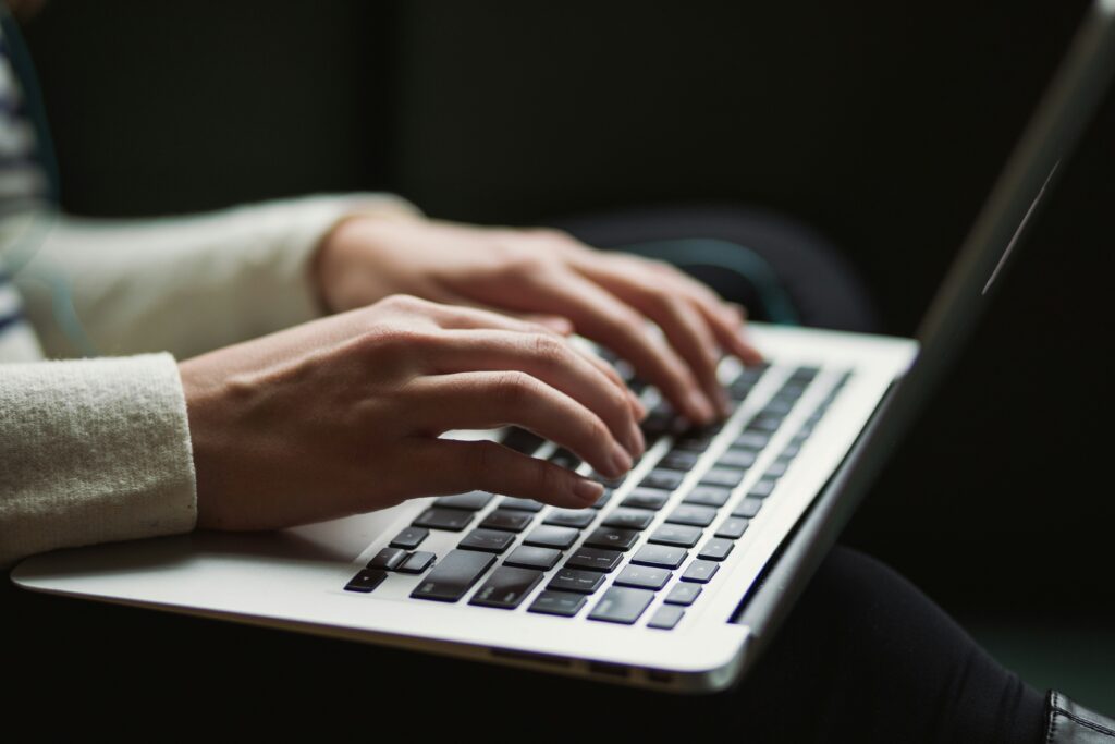 A girl typing, writing something on macbook